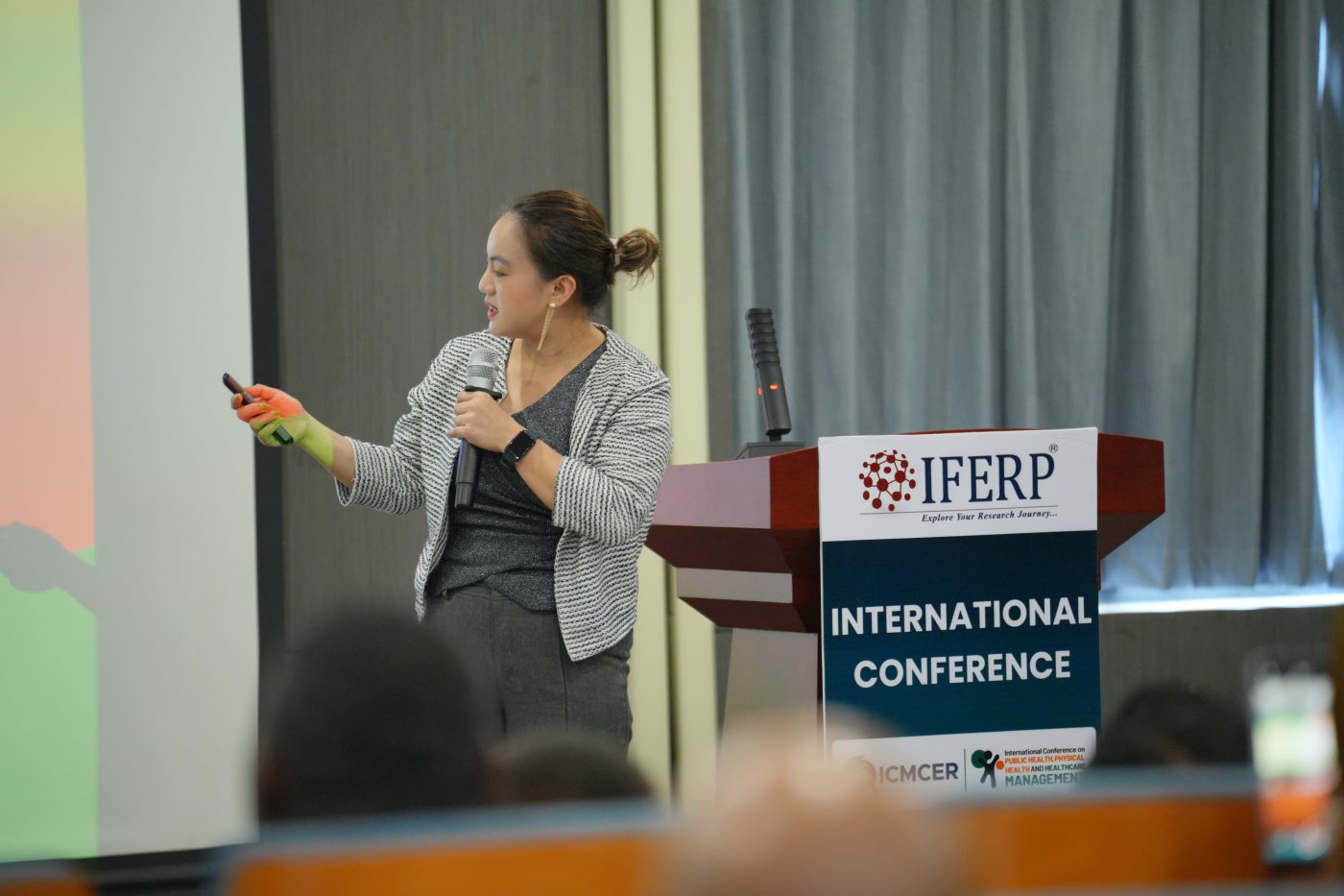 A presenter addressing the audience beside her projected slides at an IFERP conference